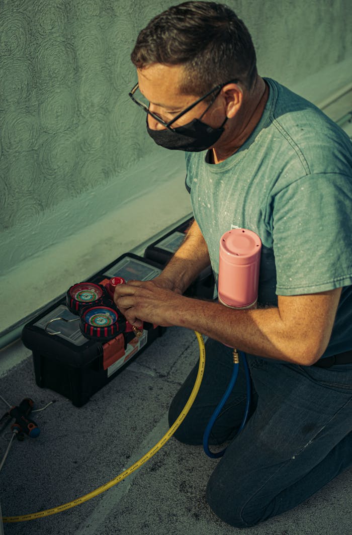 A technician kneels outdoors, performing HVAC maintenance using specialized tools, enhancing system performance.